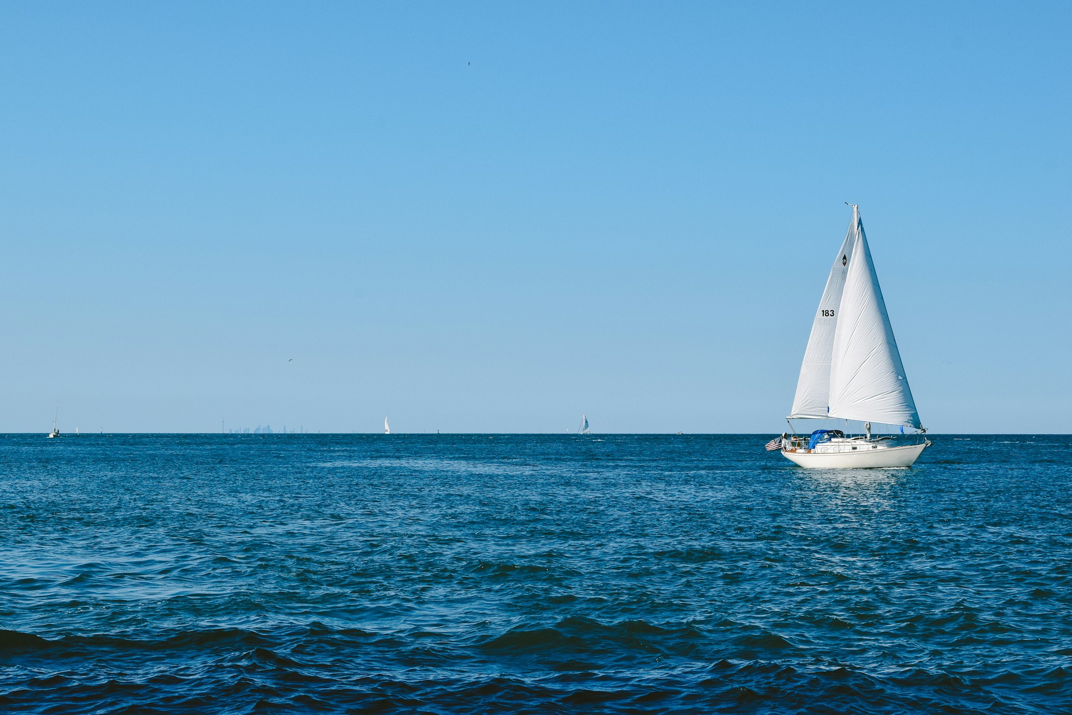 A white sailboat crossing the open horizon
