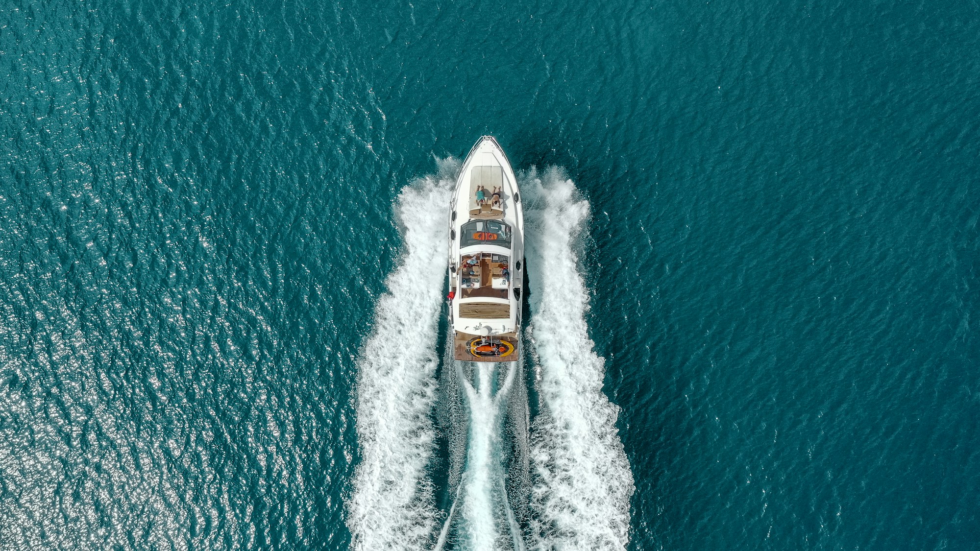 A private yacht seen from above as it crosses teal water