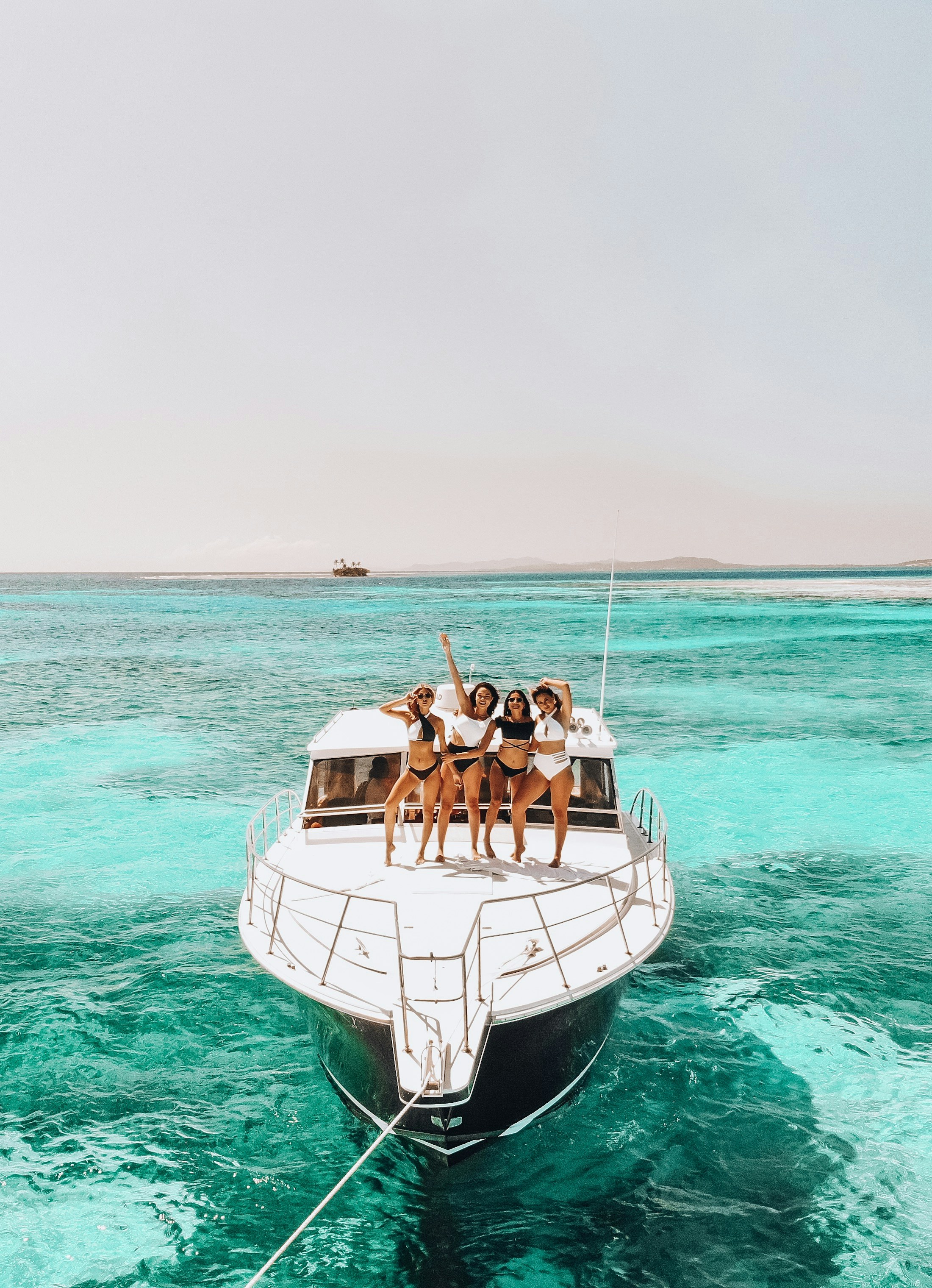 Friends gathered on the bow of a yacht over turquoise water