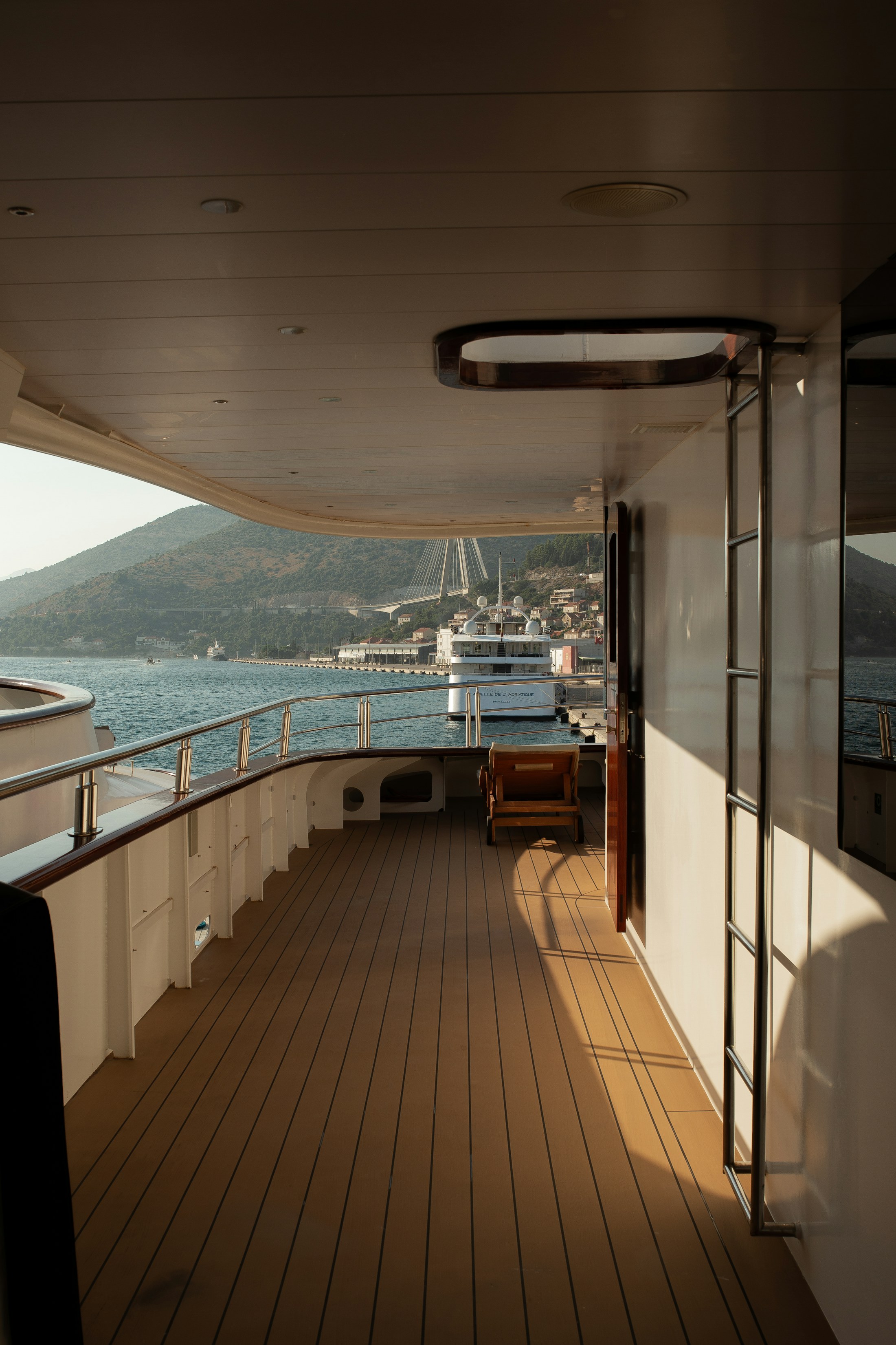 A shaded yacht deck overlooking a coastal harbor