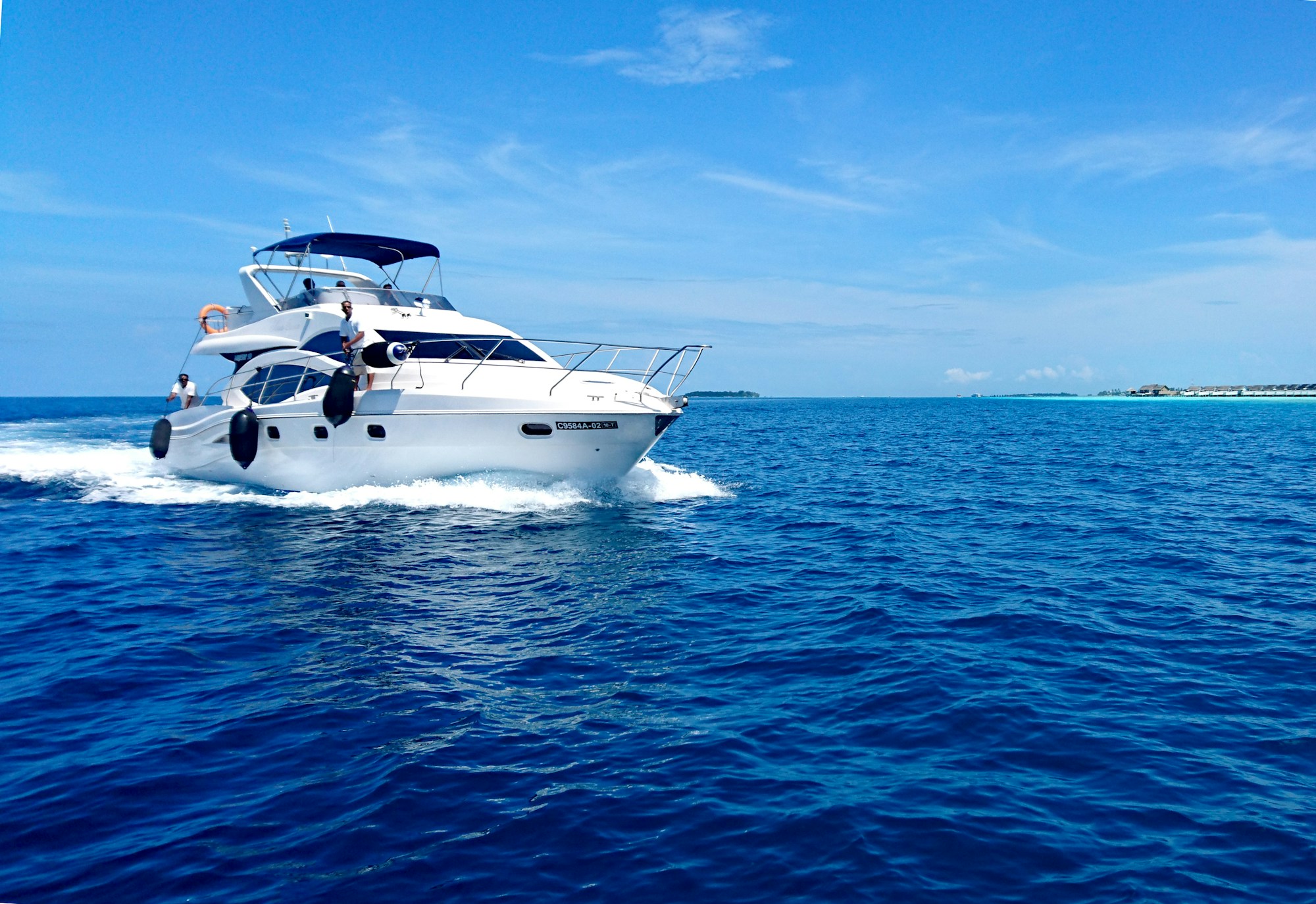 A white motor yacht crossing vivid blue water