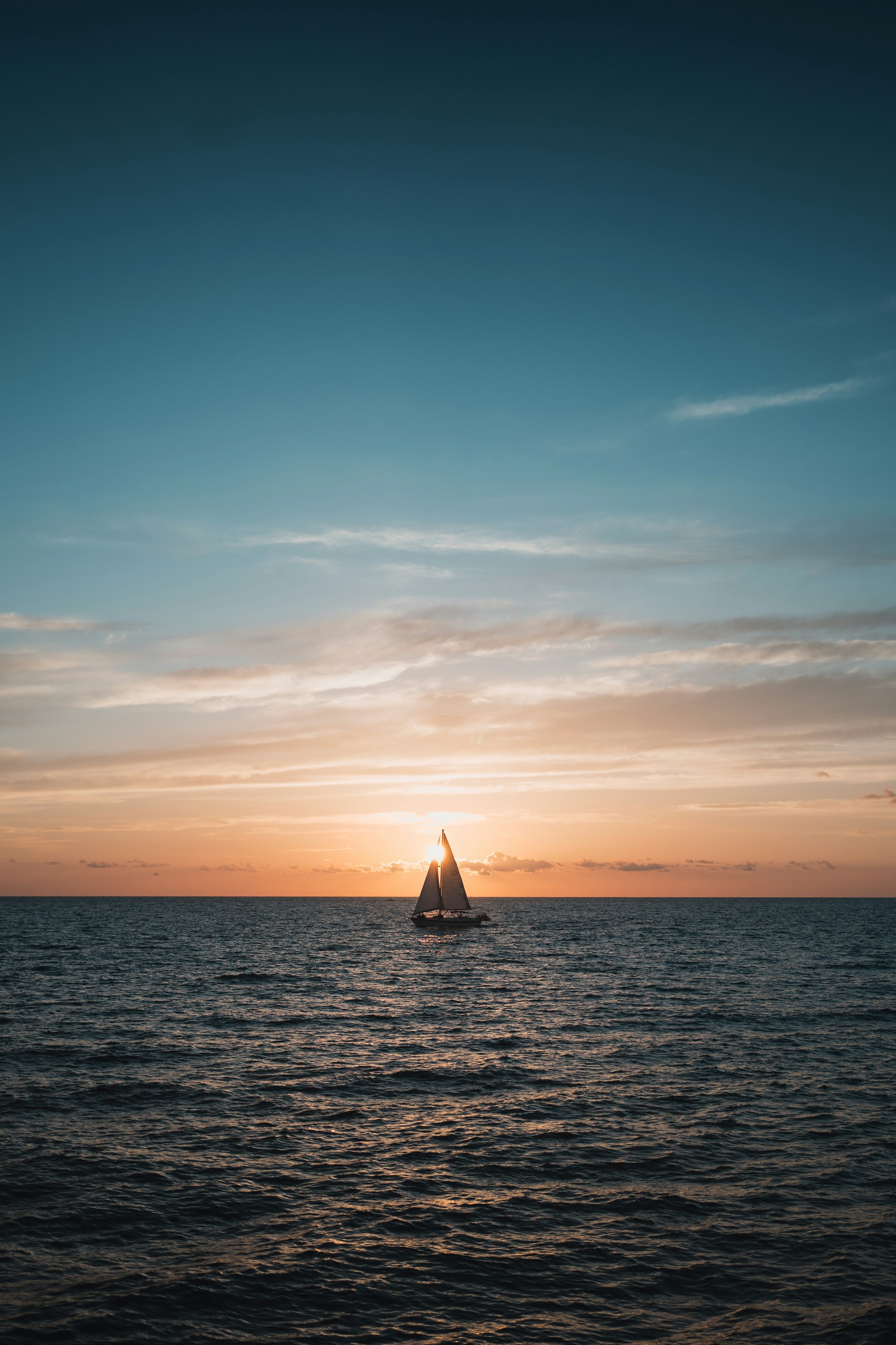 A sailboat crossing the horizon at sunset